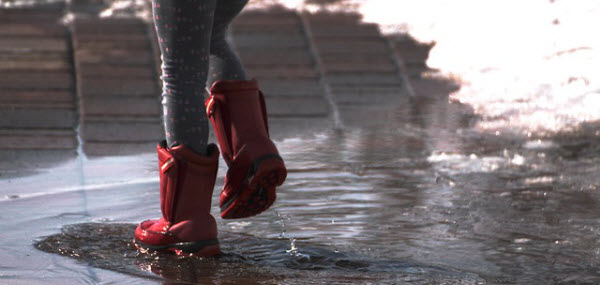 水たまりを楽しそうに歩く綺麗な足の女性