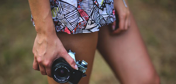 カメラを片手に持つ脚線美の女性
